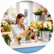 Responsable de atención al cliente atendiendo pedidos florales en una tienda luminosa