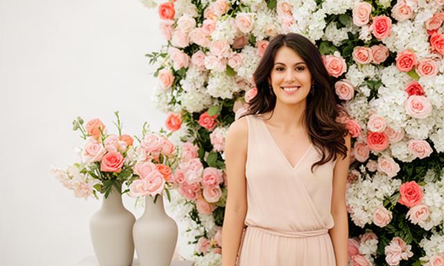 Creadora de contenido junto a un rincón floral rosa y blanco preparado para una sesión
