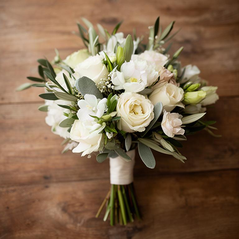 Ramo de novia con flores mediterráneas claras sobre una mesa de madera